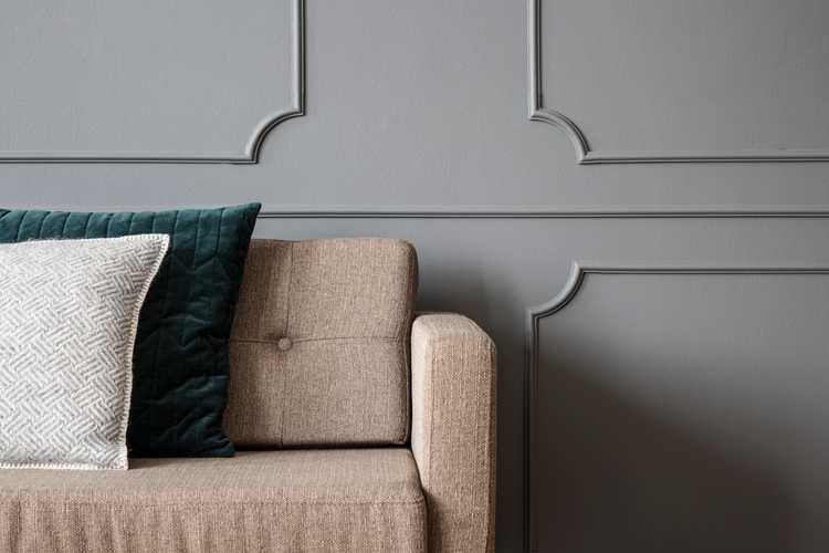 Beige soffa mot en grå vägg